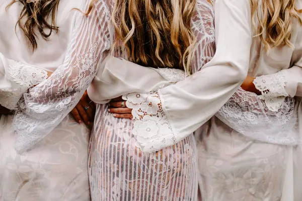 Bridal party in lace robes, arms around each other